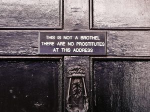 a zoomed in photo of a door with the description "this is not a brothel. there are no prostitutes at this address".